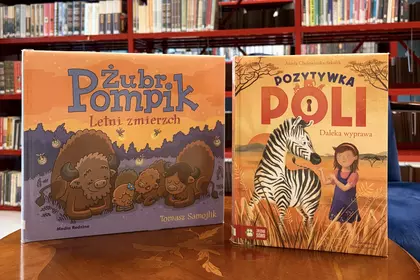 Książki „Żubr Pompik” i „Pozytywka Poli” prezentowane na bibliotecznym stoliku.