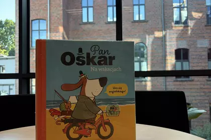 Książka „Pan Oskar na wakacjach” na tle okien Leszczyńskiej Galerii Książki.