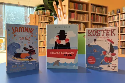 Książki o wakacyjnych przygodach prezentowane na stoliku w bibliotece.