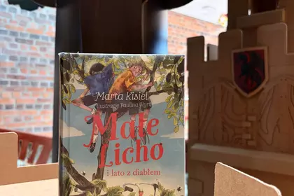 Książka „Małe Licho i lato z diabłem” na tle dziecięcego zamku.