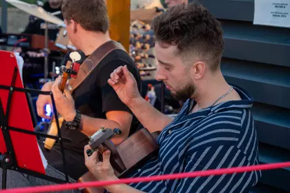 Gitarzysta akompaniuje zespołowi podczas koncertu plenerowego.