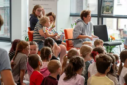 Dzieci i opiekunowie uczestniczą w spotkaniu o adopcji zwierząt.