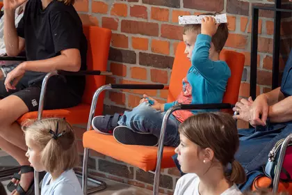 Chłopiec siedzi na krześle podczas spotkania edukacyjnego.
