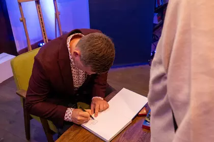 Autor podpisuje egzemplarze albumu dla czytelników.