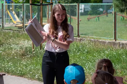 Bibliotekarka czyta dzieciom książkę podczas plenerowego spotkania Bajkomotywy.