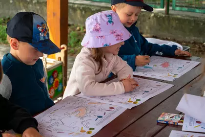 Dzieci wspólnie kolorują ilustracje przy długim stole.