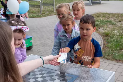 Dzieci odbierają bilety pasażera Bajkomotywy podczas zabawy.