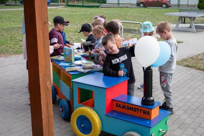 Mali czytelnicy przeglądają książki zgromadzone w Bajkomotywie.