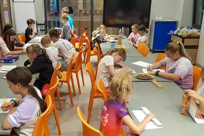 Uczestnicy wakacyjnych zajęć bawią się przy grach i łamigłówkach.