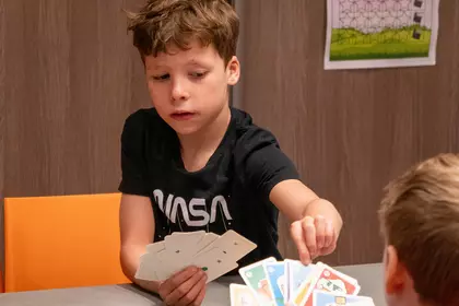 Chłopcy grają w grę karcianą przy bibliotecznym stole.