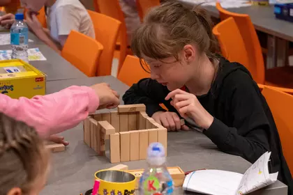 Dzieci budują konstrukcję z drewnianych klocków Jenga.