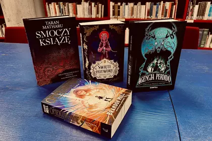 Młodzieżowe powieści fantasy i przygodowe na bibliotecznym stole.