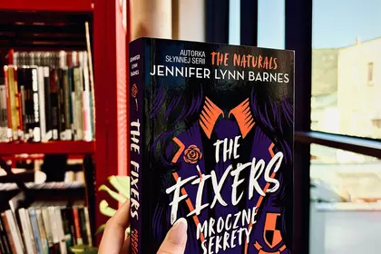 Książka „The Fixer. Mroczne sekrety” w bibliotecznej czytelni.
