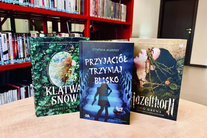 Młodzieżowe powieści fantasy prezentowane na stole w bibliotece.