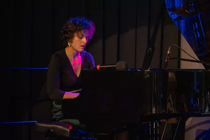 Pianistka zespołu O.N.E. gra na fortepianie podczas koncertu.