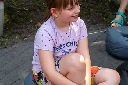 Dziewczynka siedzi na pufie i słucha czytanej opowieści.