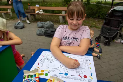 Dziewczynka koloruje ilustrację podczas bibliotecznych zajęć plenerowych.
