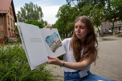 Bibliotekarka prezentuje dzieciom ilustracje z czytanej książki.