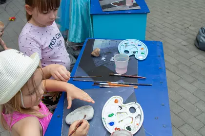 Dzieci malują kamienie podczas kreatywnych zajęć z Bajkomotywą.