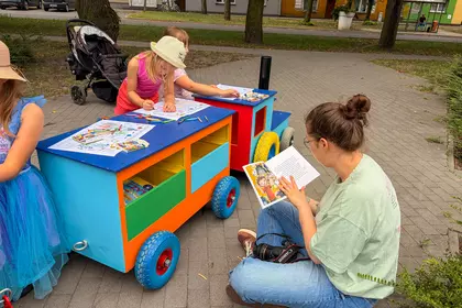 Dzieci kolorują ilustracje przy bibliotecznej Bajkomotywie na Rynku Zaborowskim.