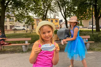 Dziewczynka prezentuje własnoręcznie pomalowany kamień podczas zajęć Bajkomotywy.