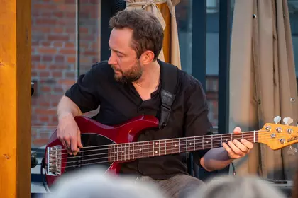 Michał Kapczuk gra na gitarze basowej podczas koncertu.