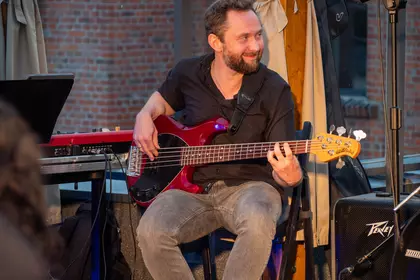 Michał Kapczuk gra na gitarze basowej podczas wieczornego koncertu.