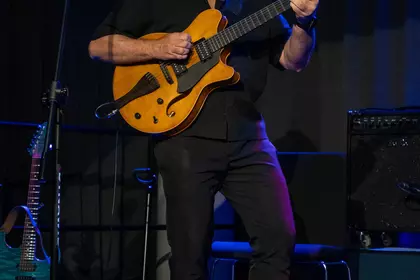 Marek Napiórkowski gra na gitarze podczas koncertu jazzowego.