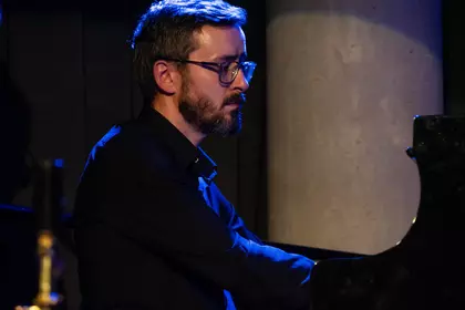 Pianista wykonuje utwór przy fortepianie koncertowym.
