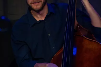 Uśmiechnięty kontrabasista podczas koncertu jazzowego.