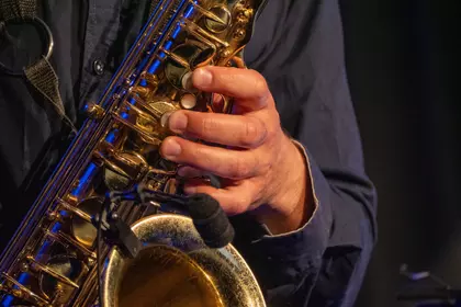 Zbliżenie na dłonie saksofonisty i instrument.