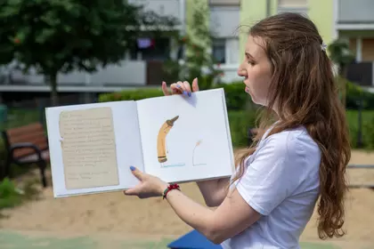 Bibliotekarka prezentuje ilustracje z książki podczas czytania na świeżym powietrzu.