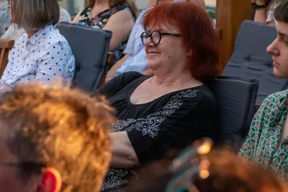 Uśmiechnięta uczestniczka koncertu słucha występu.