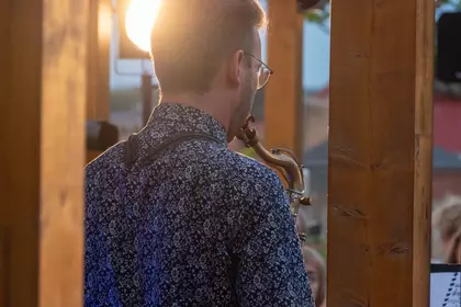 Mateusz Skrzypczak gra na saksofonie w wieczornym świetle.