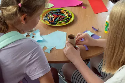 Dzieci wspólnie tworzą kolorowe ptasie domki z papieru i rolek.