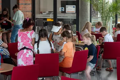 Uczestnicy wakacyjnych zajęć wspólnie wykonują papierowe ptasie domki.