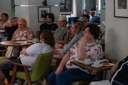 Uczestnicy spotkania o kulturze Serbii siedzą przy stolikach w Bibliotece Ratuszowej.