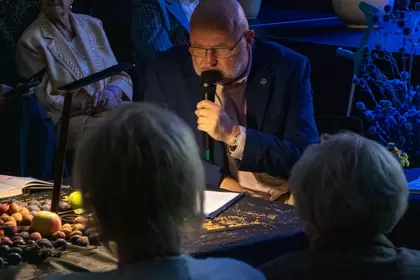 Uczestnik czyta do mikrofonu przy dekorowanym stole.