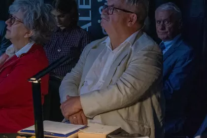 Uczestnicy wydarzenia siedzą przy stole z książkami i jesiennymi dekoracjami.