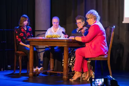 Uczestniczki czytają „Dziady” przy stole na scenie.