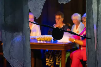 Dekoracja sali z wiszącą czarną kulą na tle czytających uczestników.