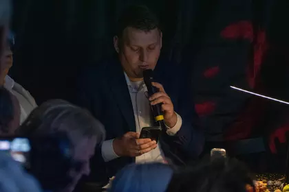 Mężczyzna czyta fragment tekstu do mikrofonu.