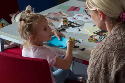 Dziecko wykonuje pracę plastyczną przy stoliku.