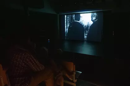 Ekran kinowy na sali audiowizualnej, uczestnicy oglądają film.