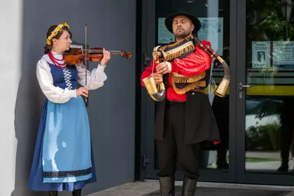 Muzycy w strojach ludowych podczas występu przed biblioteką.