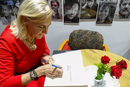 Autorka biografii podpisuje książkę podczas spotkania.