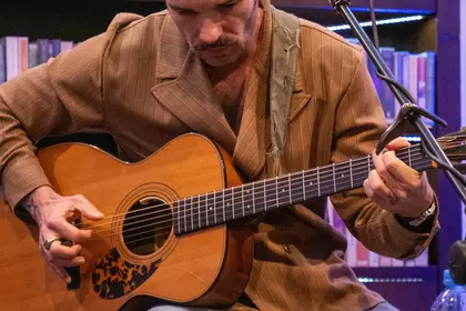 Gitarzysta grający na gitarze akustycznej podczas koncertu.