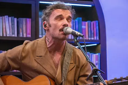 Gitarzysta śpiewający podczas koncertu w Bibliotece Ratuszowej.