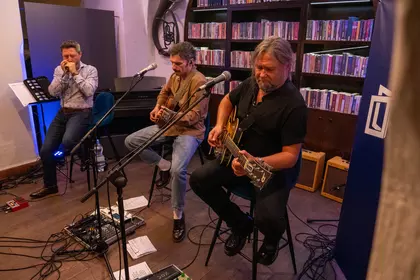 Trzej muzycy grający koncert przed publicznością.
