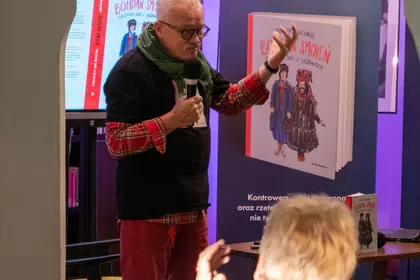 Krzysztof Deszczyński podczas spotkania, w tle książka o Bohdanie Smoleniu.